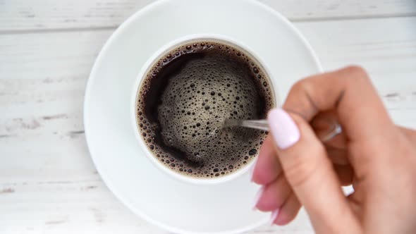 Top View Female Hand Mixing Black Coffee in Cup Use Spoon