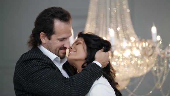 Portrait of the Newlyweds in Profile Against the Background of a Crystal Chandelier