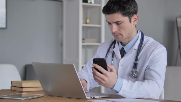 Doctor Working on Laptop and Using Smartphone