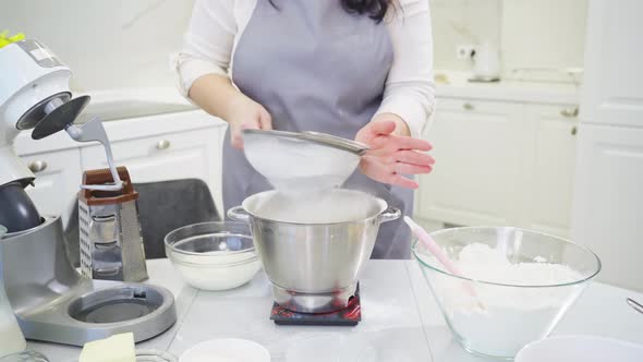 Cook Sifts the Flour Through a Sieve to Prepare Dough in a Mixer Bowl on Scale