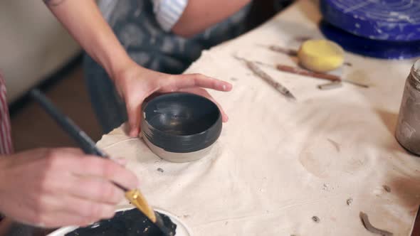 Female Artist Is Coloring New Clay Cup By Black Dye in Table of Workshop