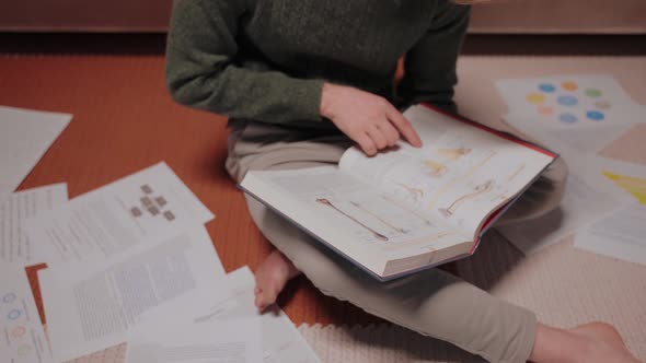 Young Man Sits on the Floor Surrounded By Papers and Notes Listens Music