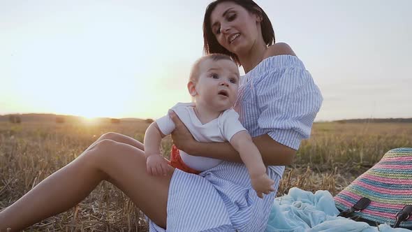 Young Woman in a Light Dress is Sitting on the Grass in the Field alt
