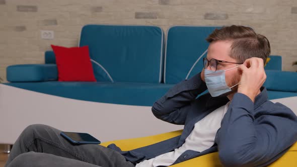 Close Up of an Young Man Put on a Medical Mask on His Face and Start To Talks Online.