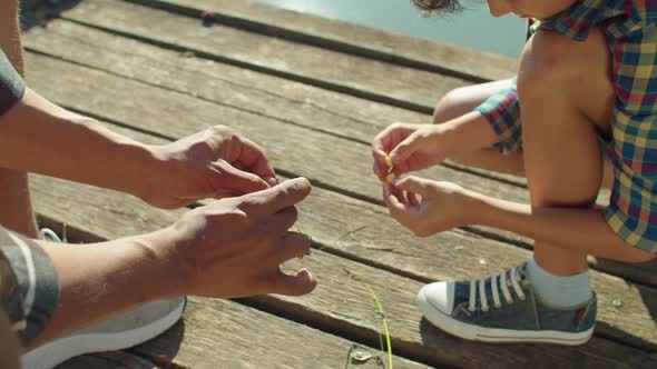 Closeup of Diverse Human Hands Putting Baits on Fishing Hooks