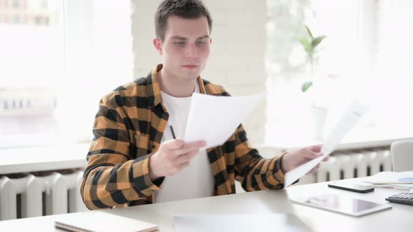 Tense Young Man Feeling Sad After Reading Documents