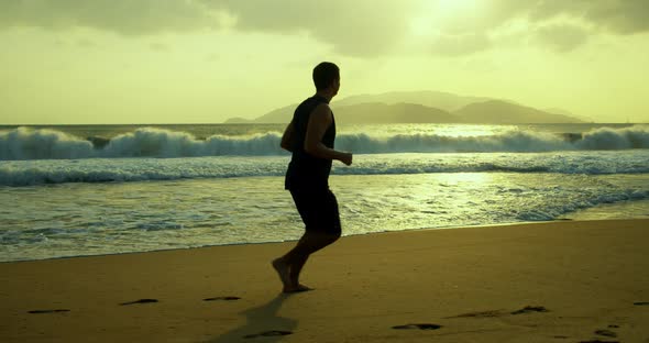 Silhouette of a Young Caucasian Man Exercising Outdoors on the Background of a Beautiful Sea