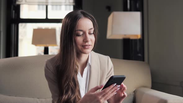 Smiling Woman Using Mobile Phone in Hotel Lounge