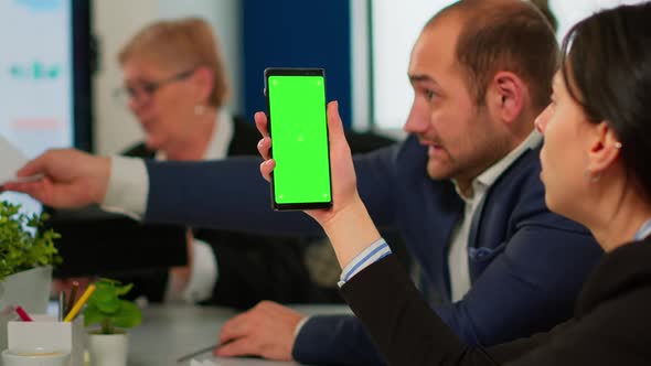 Businesspeople Analysing Reports Sitting at Desk While Employee Holding Phone with Green Screen