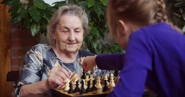 Grandmother and Granddaughter Play Chess at Home
