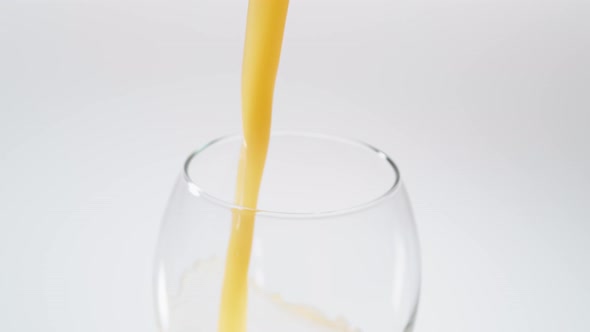 Camera follows pouring orange juice into glass. Slow Motion.