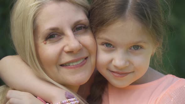 Close-up Portrait Smiling Blond Mother and Her Little Daughter Hugging in the Summer Park