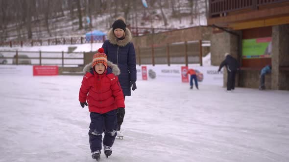 Young Mom and a Little Boy on a Rink. Little Boy Learn How To Ice-skate. Winter Activities Concept