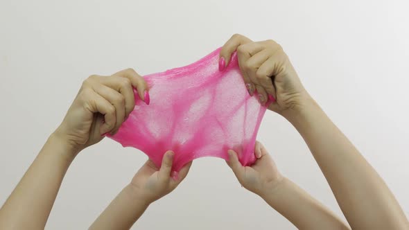 Woman and Child Hands Playing Oddly Pink Slime on White Background. Antistress
