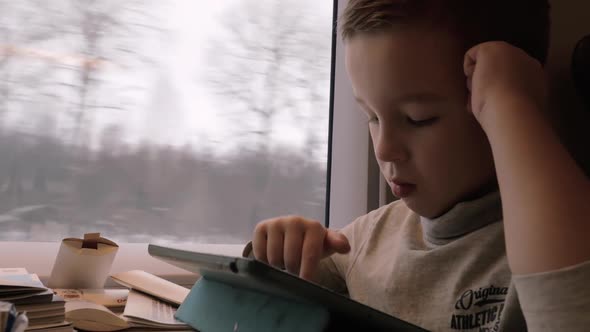 Kid Passing the Time with Pad During Train Journey