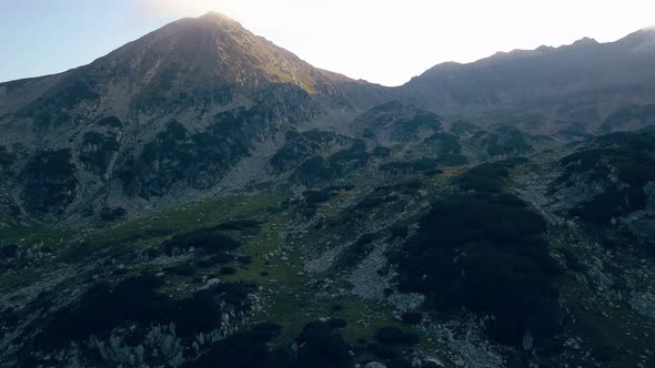 Wide aerial drone slowly climbing up through a mountain range.