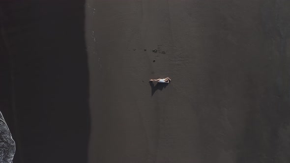 Aerial View of a woman on the beach, Praia do Areal, Azores, Portugal. alt