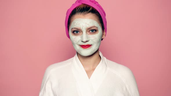 Girl with a Mask on Her Face Toss Up an Apple on a Pink Background. Beautiful Girl with Cosmetic