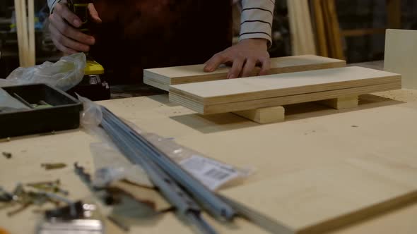 Woman drilling plywood at workshop