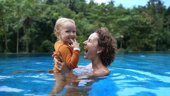Mom and Baby in the Pool are Happy Together Laughing with Pleasure