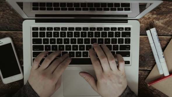 Businessman Typing On His Laptop On a Wooden Desk Table