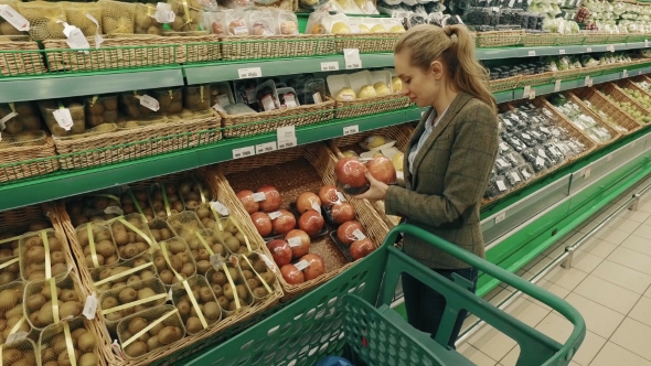 Young Blond Woman Walk Along Shelves With Fruits In Supermarket And Buy Papaya