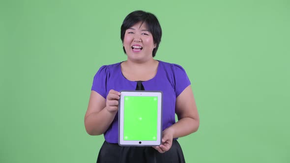 Happy Young Overweight Asian Woman Talking While Showing Digital Tablet