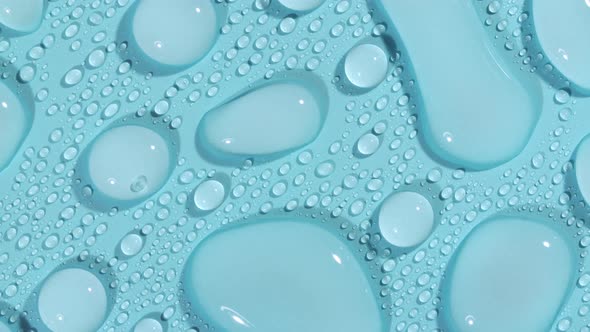 Macro Shot of Cosmetic Moisturizing Drops of Liquid on a Greenblue Pastel Background