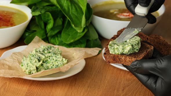 Knife spreading cream cheese on piece of bread