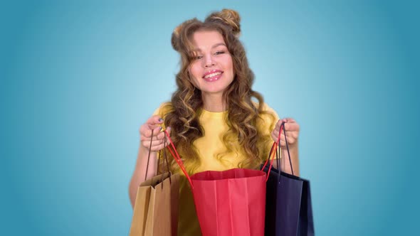 a Beautiful Young Girl in a Yellow Tshirt After Shopping Opens the Package and Enjoys Shopping