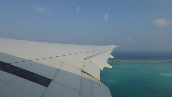 Wing Of Airplane Flying Above Ocean And Maldives  4 alt