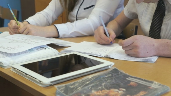 Two Schoolgirls Sit At Desk In School