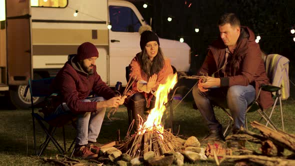 Girl Warming Up Her Hands While Her Friend Making the Fire Stronger