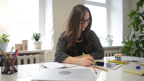 Young Girl Writing and Working on Tablet at Same Time alt