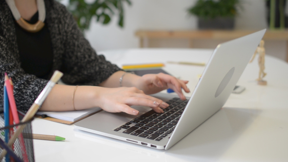 Designer Woman Typing on Laptop at Work in Office