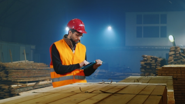 Warehouse Worker Uses a Tablet, According To The Quantity Of Goods Or Construction Materials