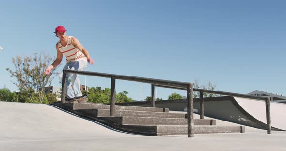 Low section of caucasian man riding and jumping on skateboard on sunny day