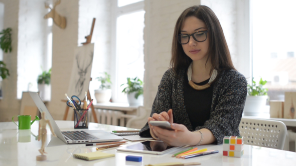 Female Designer Using Phone, Working in Office alt