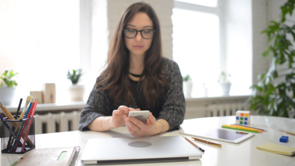 Girl Using Smartphone in Creative Office