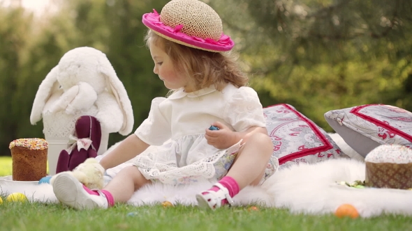 Happy Child Sits On a Meadow Around Easter Decoration