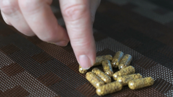 Hand Finds Pills In The Form Of Capsule On a Table