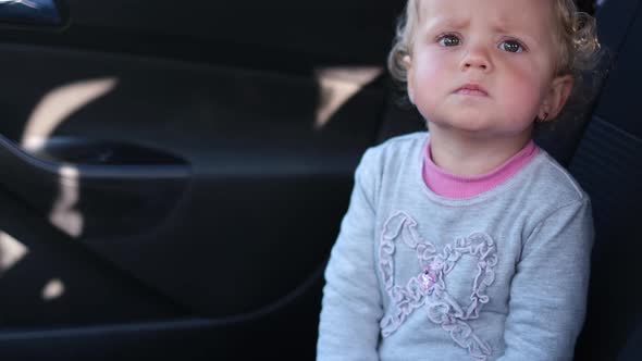 Little Girl Applauds in the Palm of Her Hand Sitting in the Car