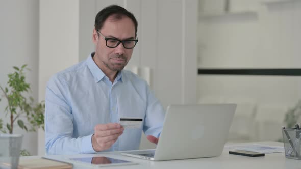 Middle Aged Man Making Successful Online Payment on Laptop