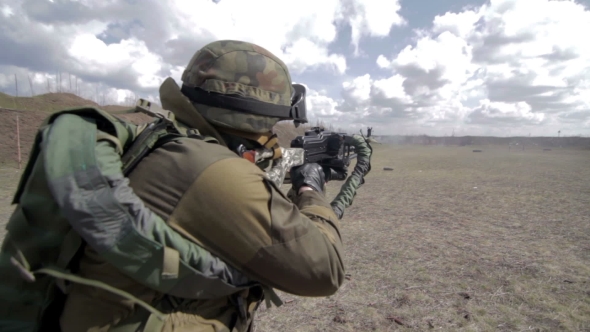 A Soldier With a Machine Gun On a Military Firing Range Shooting At a Target.