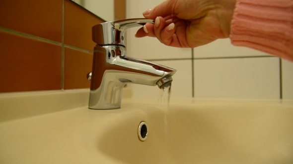 Female Hand Opens Water Tap And Try  Water Temperature