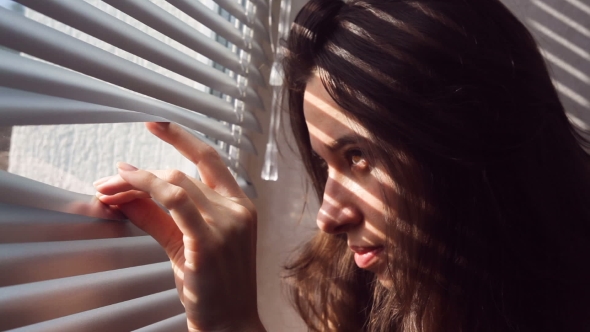 Woman Hand Pushing The Blinds And Looking Out Window