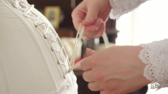 Tying vintage corset on woman