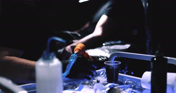 Tattoo Close-up. The Master Performs Tattoo Work in a Dark Tattoo Parlor.