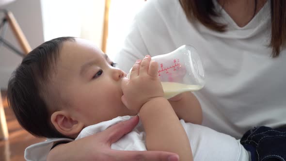 Asian Mother Feeding a Male Baby with Milk Bottle