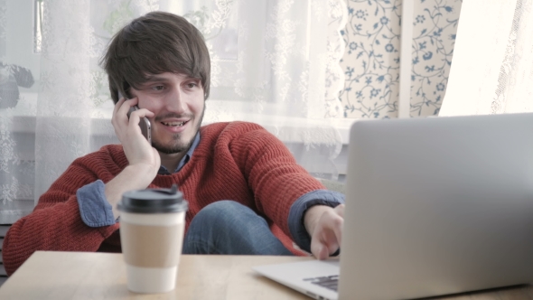 Happy Young Man Freelancer Working With Modern Laptop And Phone In Cafe Taking Cup Of Coffee